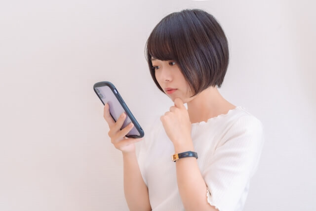 スマホを見て考えている女性　イメージ画像