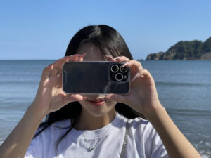 スマホで海や浜辺の写真を撮っている女性　イメージ画像