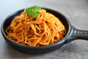 フライパンの中のミートソースで和えたパスタ　イメージ画像